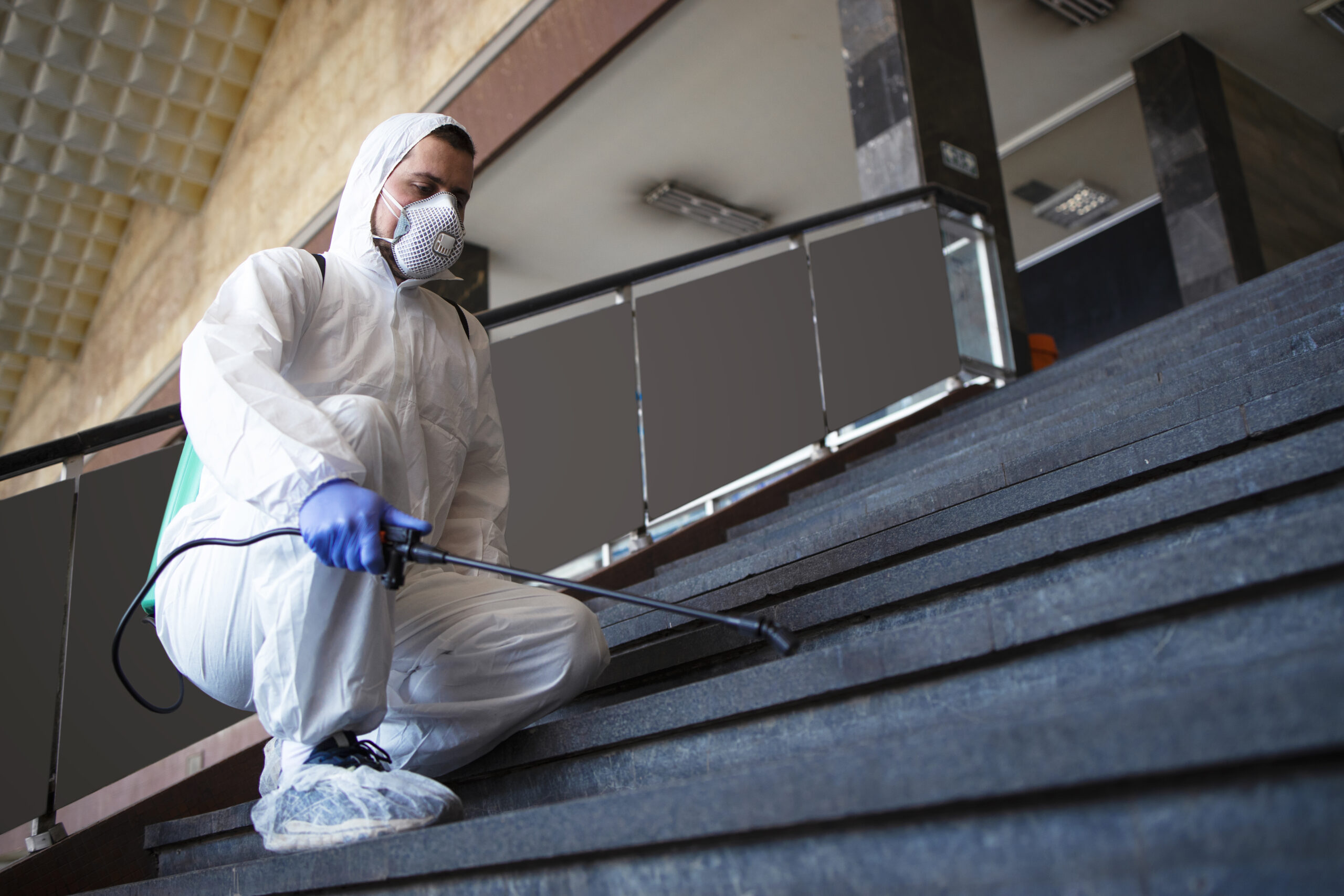 Worker in protective suit performing industrial cleaning and dust control in a commercial facility